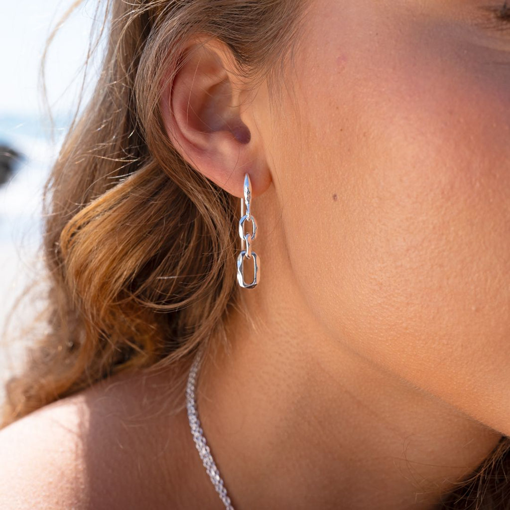Close-up of a person wearing a silver chain earring.